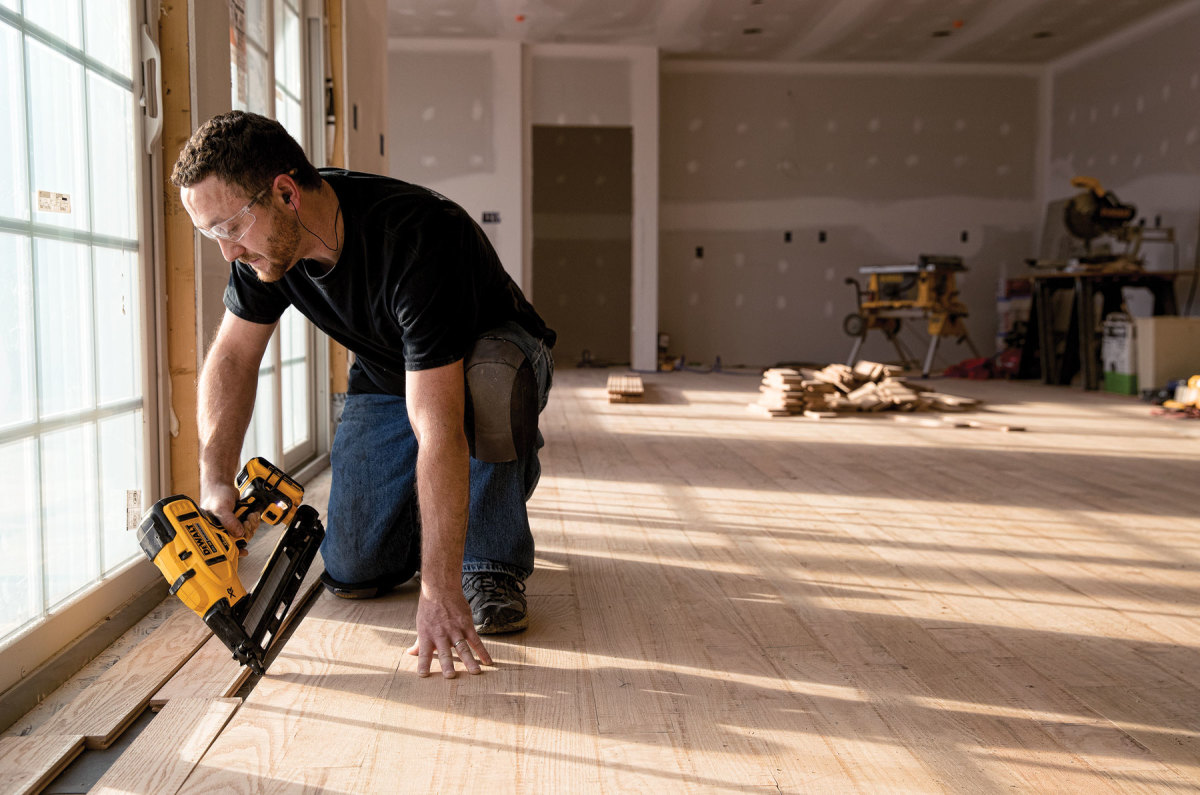 Photo of man using a power nailer to lay a floor